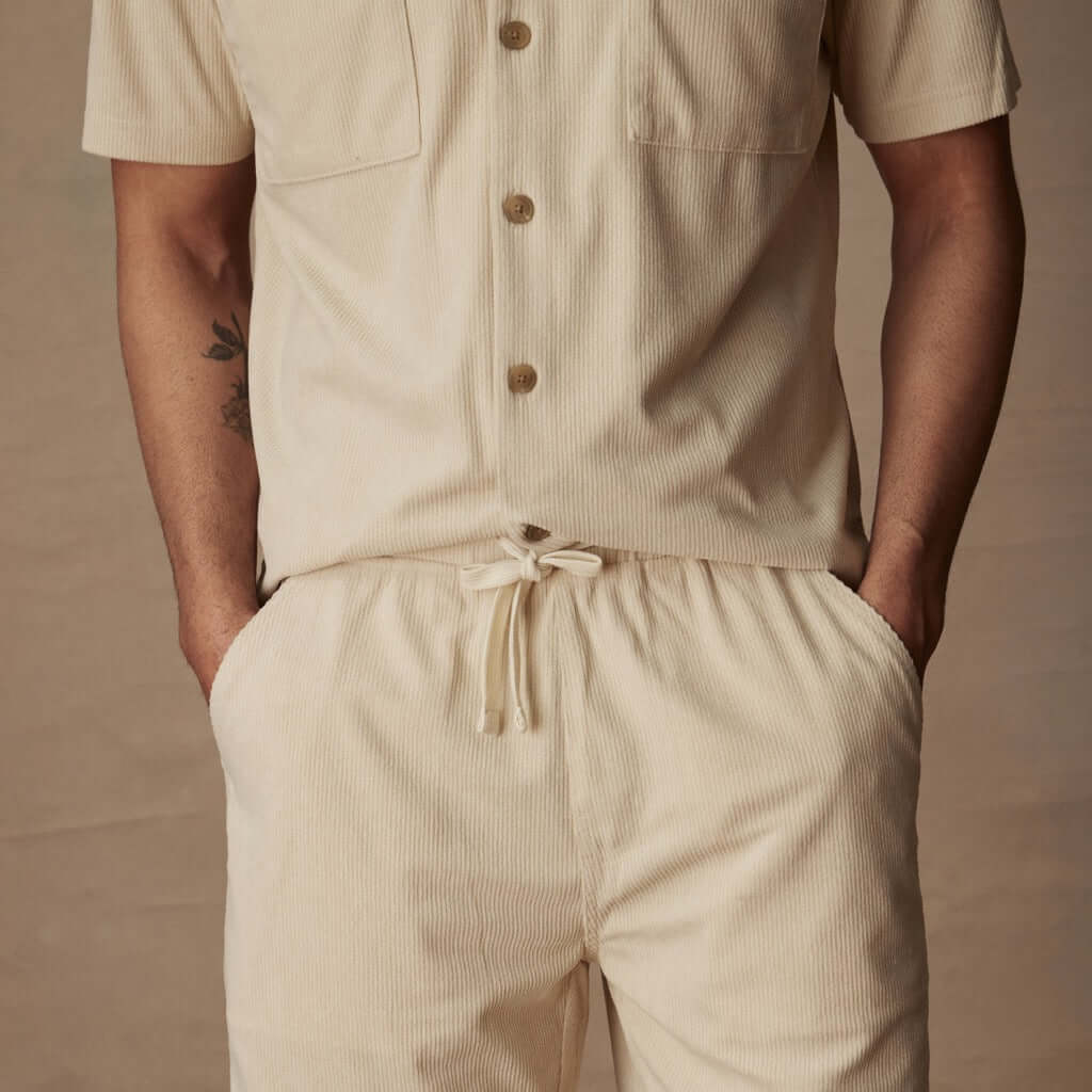 Men's 6" corduroy cabana short set in cream, featuring adjustable drawstring, buttoned shirt, and side pockets.