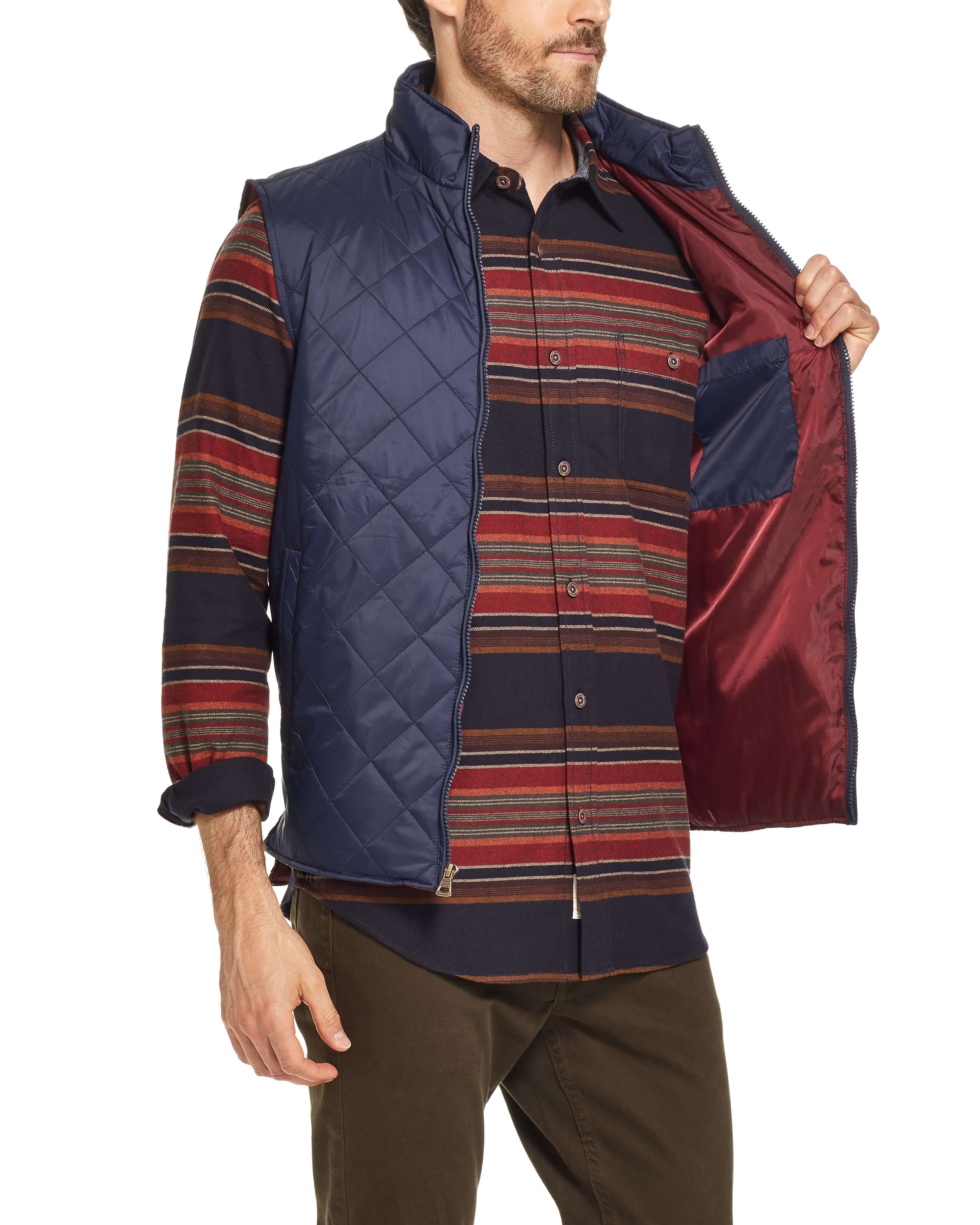 Man in a navy diamond quilted vest with a striped shirt, showcasing the inside pocket and comfortable fit.