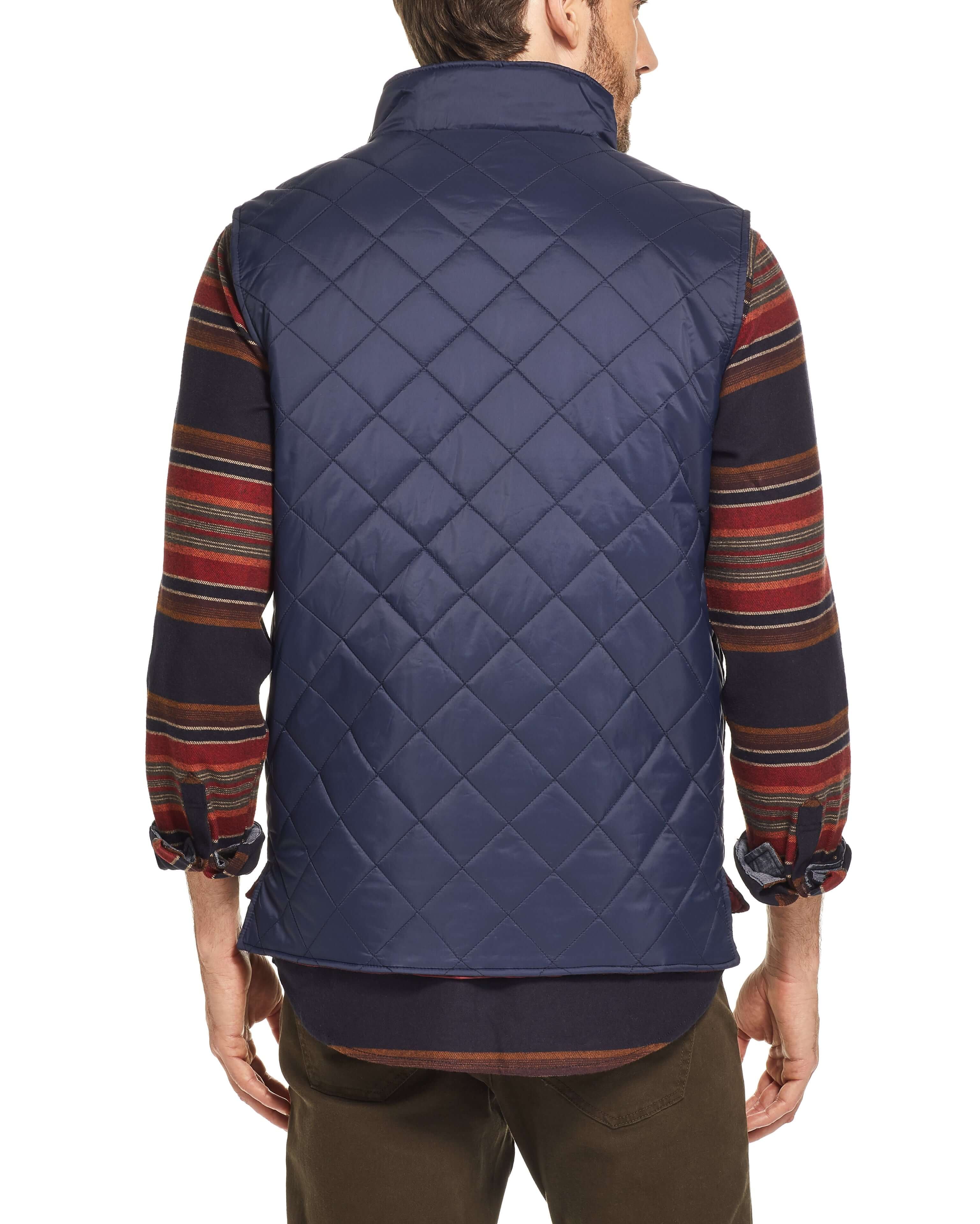 Back view of a man in a navy diamond quilted vest, showcasing its lightweight design and classic fit.