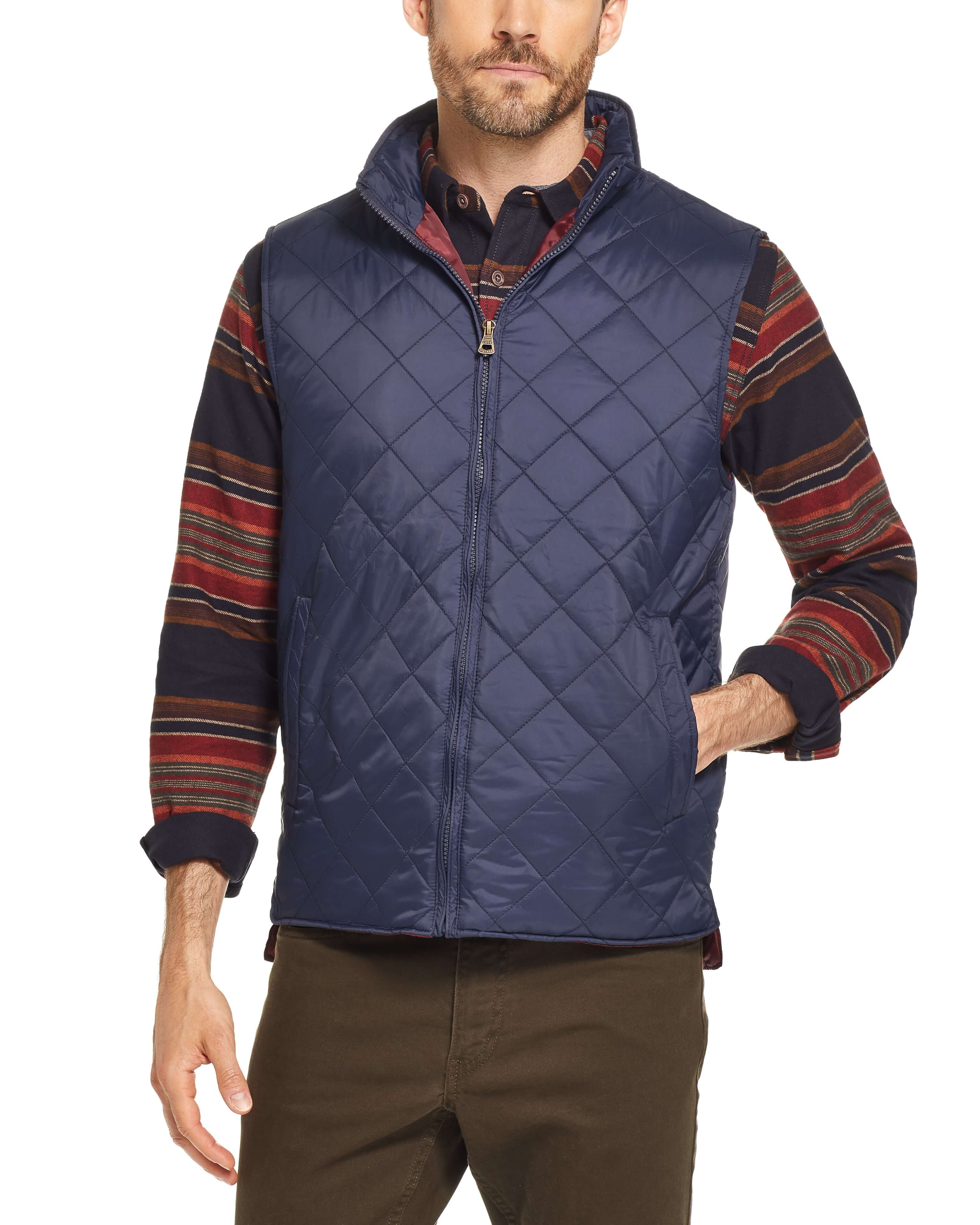 Man wearing a navy diamond quilted vest with a stand up collar, showcasing a classic fit and hand warmer pockets.