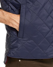 Close-up of a hand inside the pocket of a navy diamond quilted vest, showcasing its lightweight, windproof design.