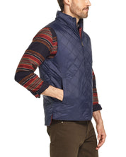 Man wearing a navy diamond quilted vest with a stand-up collar and hand warmer pockets, perfect for mild weather.