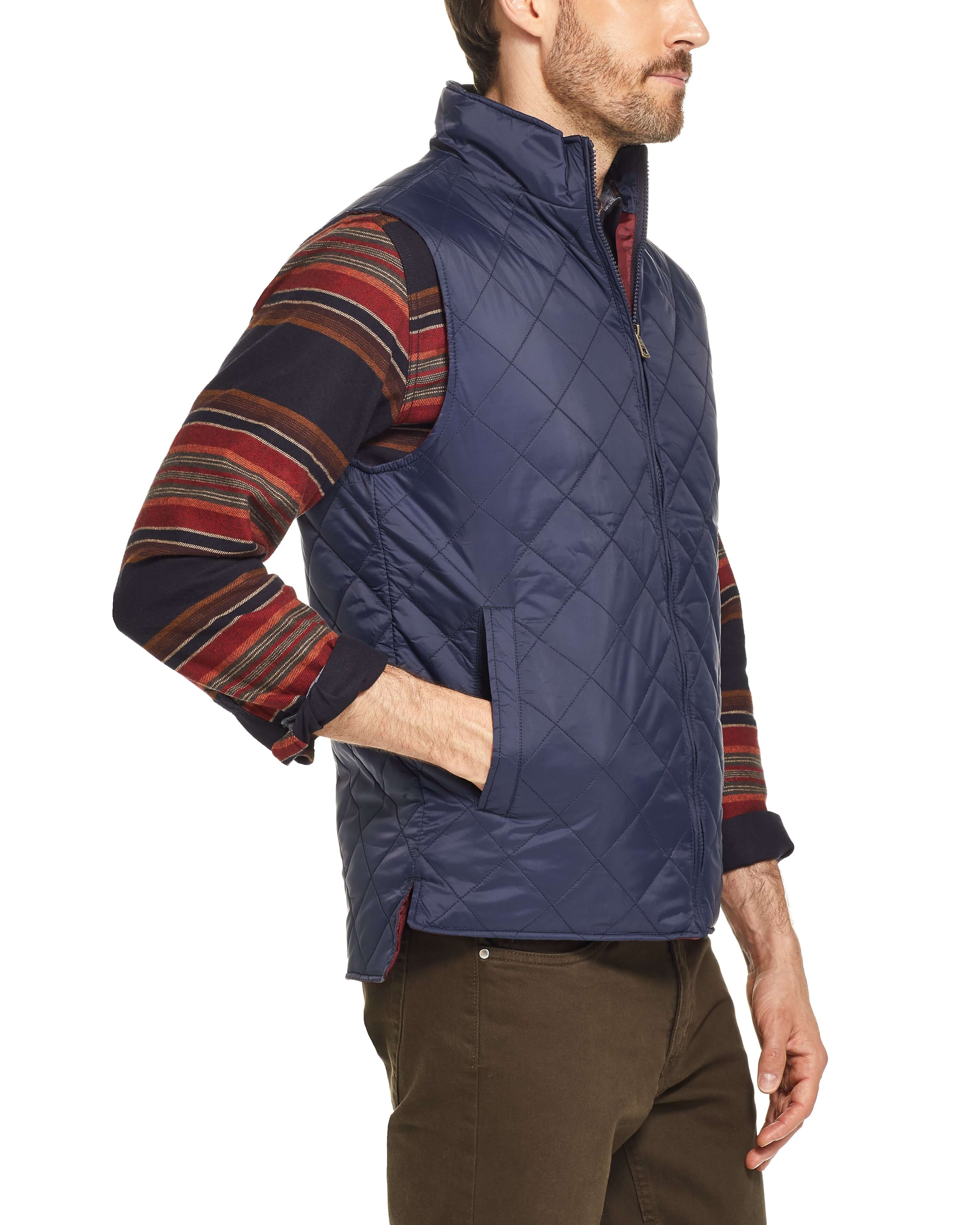 Man wearing a navy diamond quilted vest with a stand-up collar and hand warmer pockets, perfect for mild weather.
