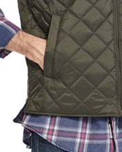 Close-up of a man's hand in the pocket of a diamond quilted vest in rosin, showcasing stylish and functional design.