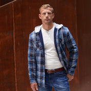 Sherpa Lined Hooded Shirt Jacket In Blue worn by a male model in a casual setting with jeans.