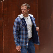 Sherpa Lined Hooded Shirt Jacket In Blue displayed on a model, showcasing its rugged twill fabric and cozy design.