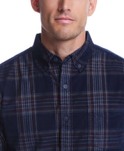 Close-up of a man wearing a blue plaid corduroy shirt with button down collar and buttoned chest pocket.
