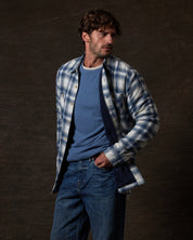 Model wearing the Sherpa Lined Flannel Shirt Jacket in Iron Blue over a blue sweater, showcasing its cozy design.