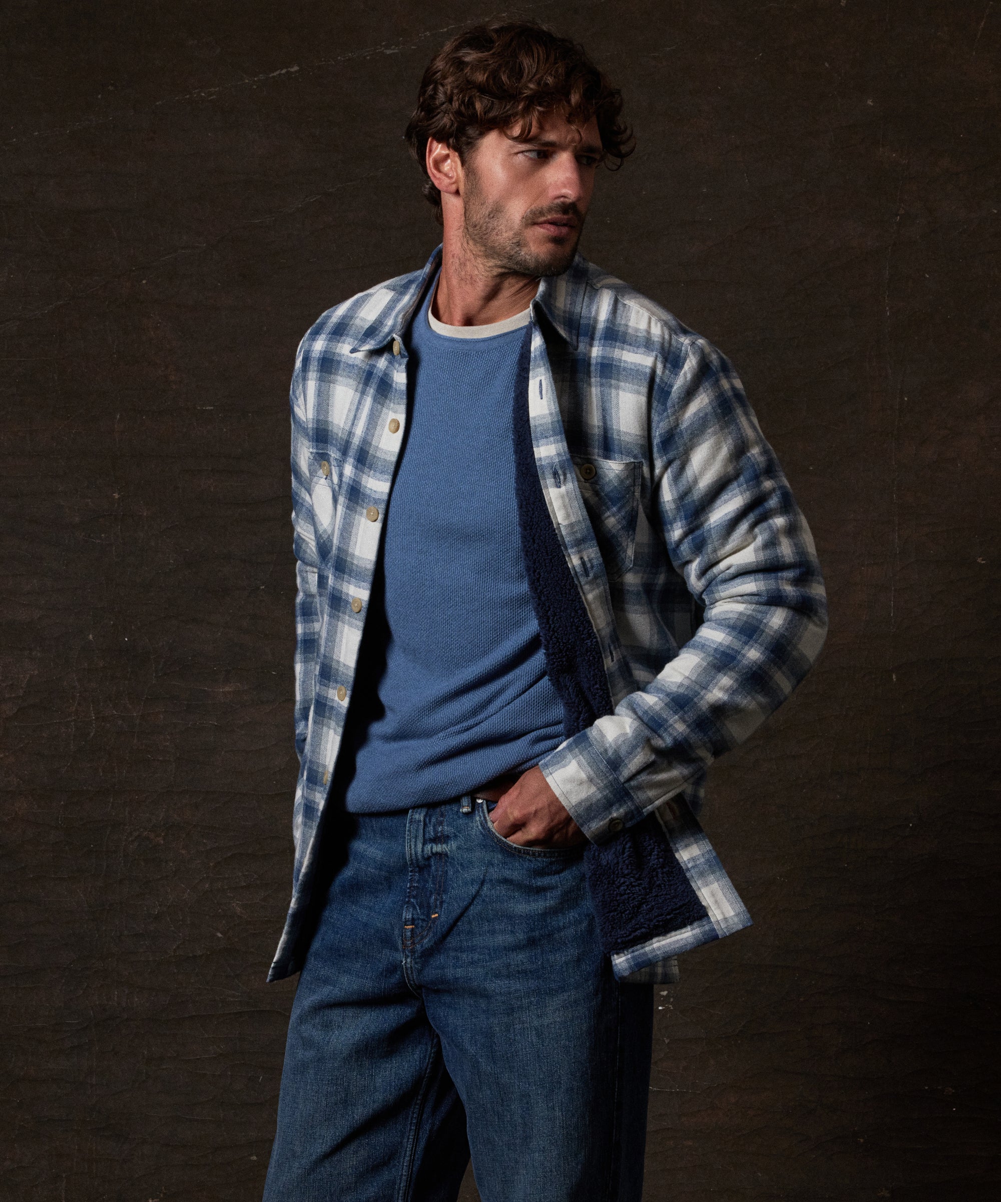 Model wearing the Sherpa Lined Flannel Shirt Jacket in Iron Blue over a blue sweater, showcasing its cozy design.
