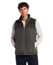 Sherpa Lined Mixed Media Puffer Vest in Kambaba Olive worn by a model, featuring durable fabric and corduroy shoulder panels.