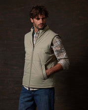 Model wearing a Matte Coated Shell Puffer Vest in Abbey Stone against a dark background, showcasing its sleek design.