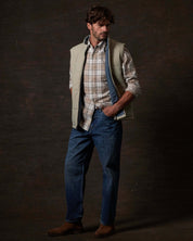 Model wearing Matte Coated Shell Puffer Vest in Abbey Stone with plaid shirt and jeans, showcasing modern rugged utility.
