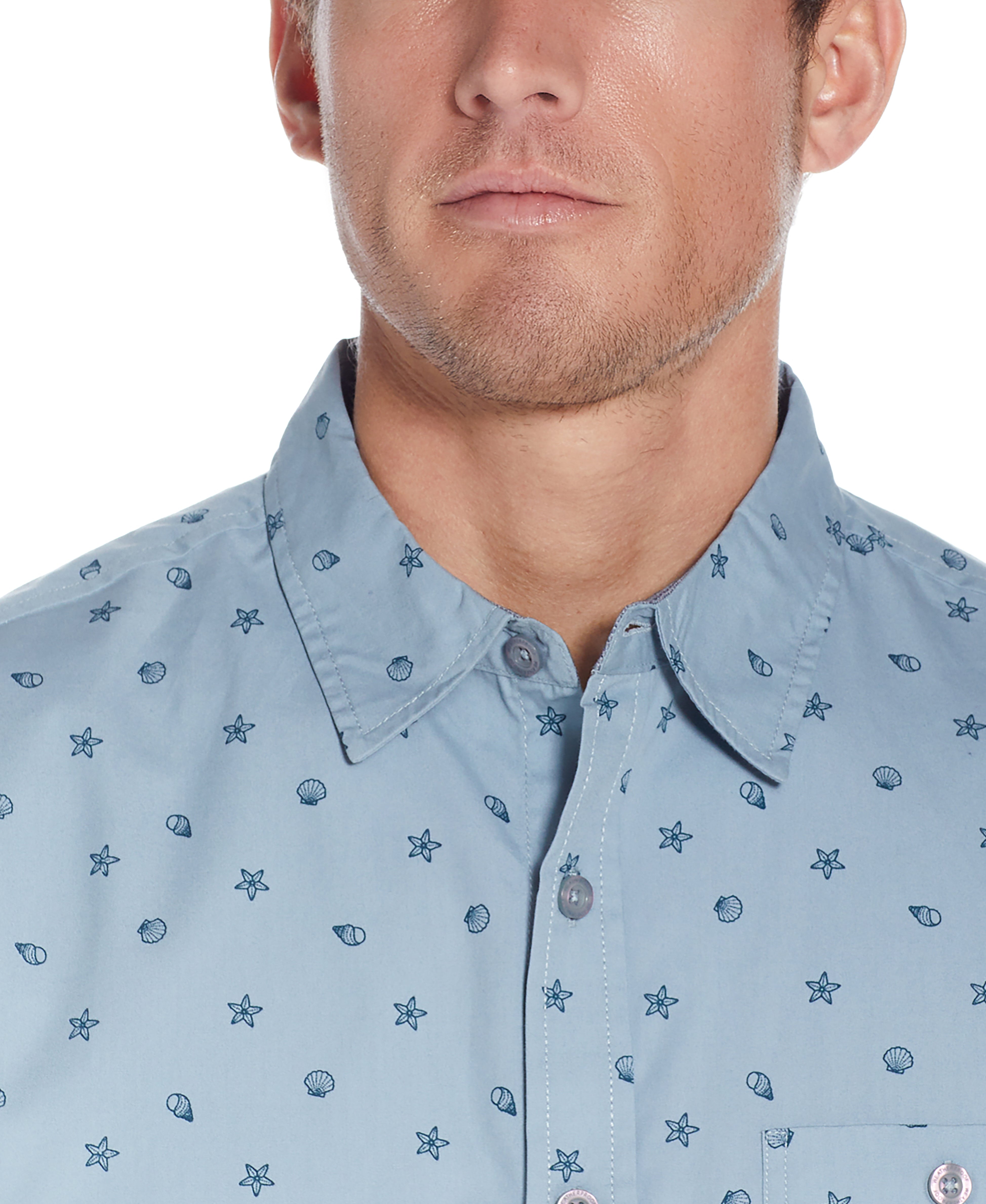 Close-up of a man wearing a Poplin Seashell Printed Shirt In Dusty Blue with seashell and star prints.