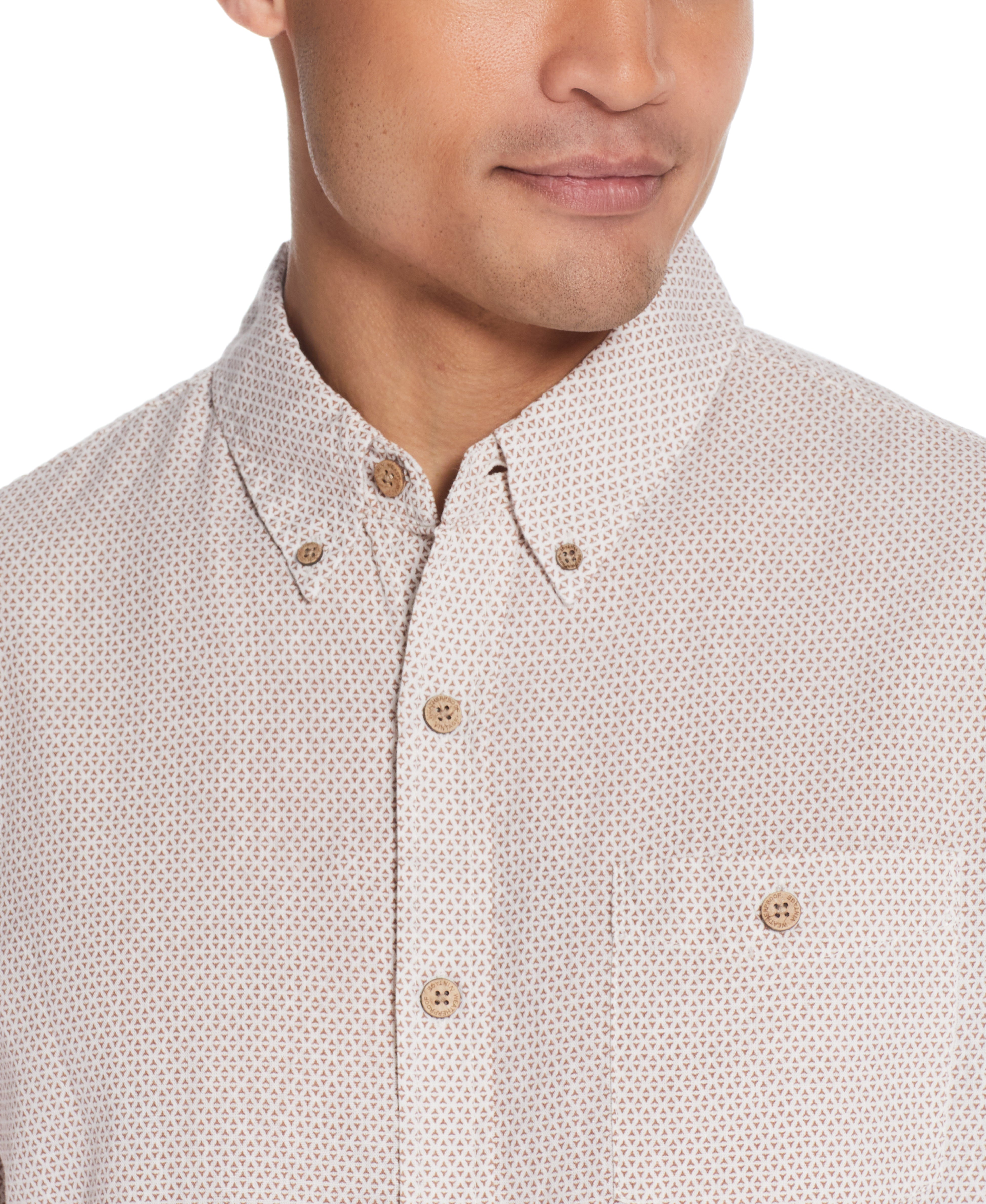 Close-up of a man wearing a Mini Geo Print Shirt In Cinnamon Stick with a relaxed fit and button detail.