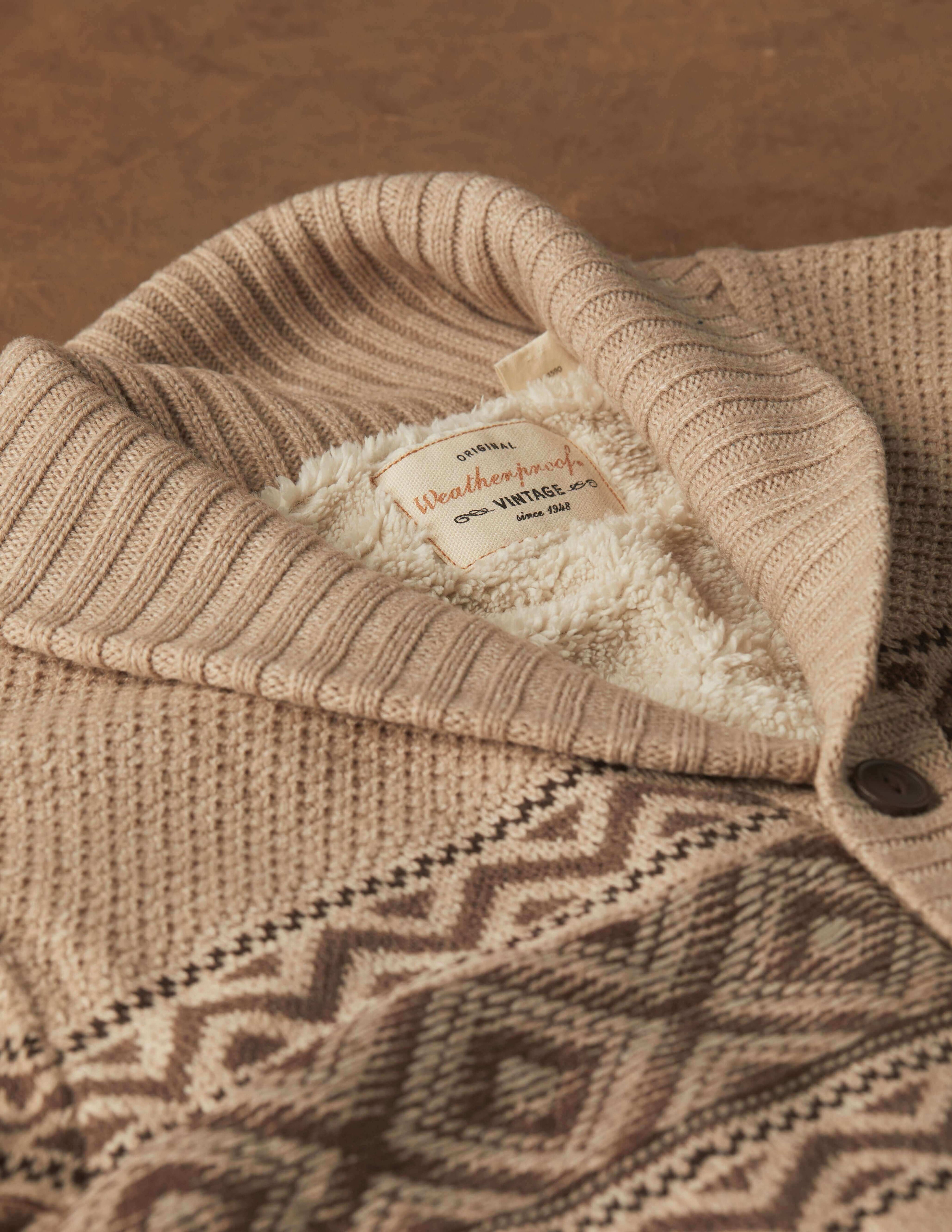 Close-up of a cozy beige knitted sweater with a geometric pattern and soft lining peeking from the collar.