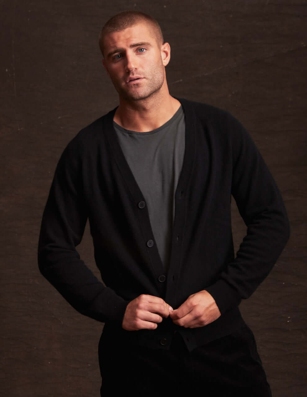 Model wearing a black cashmere cardigan over a grey shirt, showcasing its soft and lightweight design.