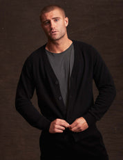 Model wearing a black cashmere cardigan over a grey shirt, showcasing its soft and lightweight design.