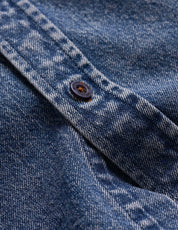 Detail view of a button on the Denim Shirt In Acid Blue showcasing its soft, faded texture and rugged quality.