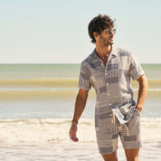 Man wearing a Jacquard Resort Shirt in Cream/Navy on the beach, showcasing a stylish vacation look.