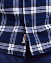 Close-up of blue plaid flannel shirt featuring button-down collar and breast pocket, ideal for rugged, rustic style.