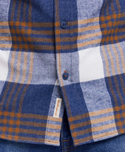 Close-up of a blue and gold plaid flannel shirt featuring a button-down collar and buttoned breast pocket.