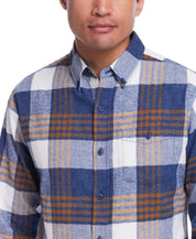 Man wearing a blue plaid long sleeve brushed flannel shirt with button-down collar and breast pocket.