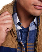 Close-up of a man wearing a blue plaid long sleeve brushed flannel shirt under a tan jacket.