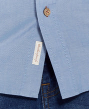 Close-up of Long Sleeve Chambray Shirt In Chambray Blue showing button and label detail.