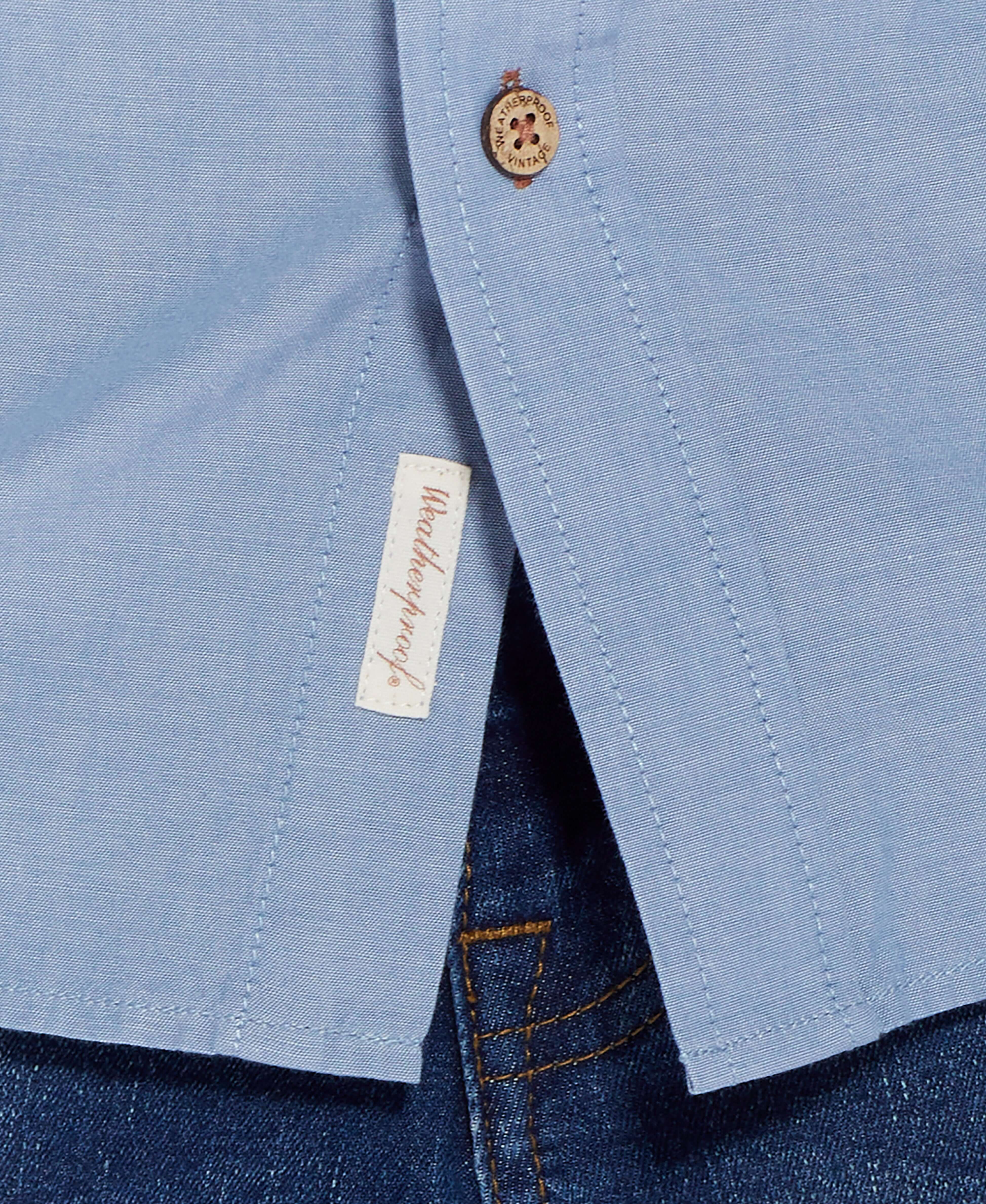 Close-up of Long Sleeve Chambray Shirt In Chambray Blue showing button and label detail.