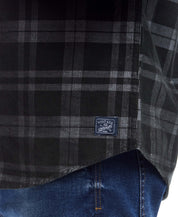 Close-up of a vintage label on a long sleeve plaid cord shirt in forest night, paired with denim jeans.