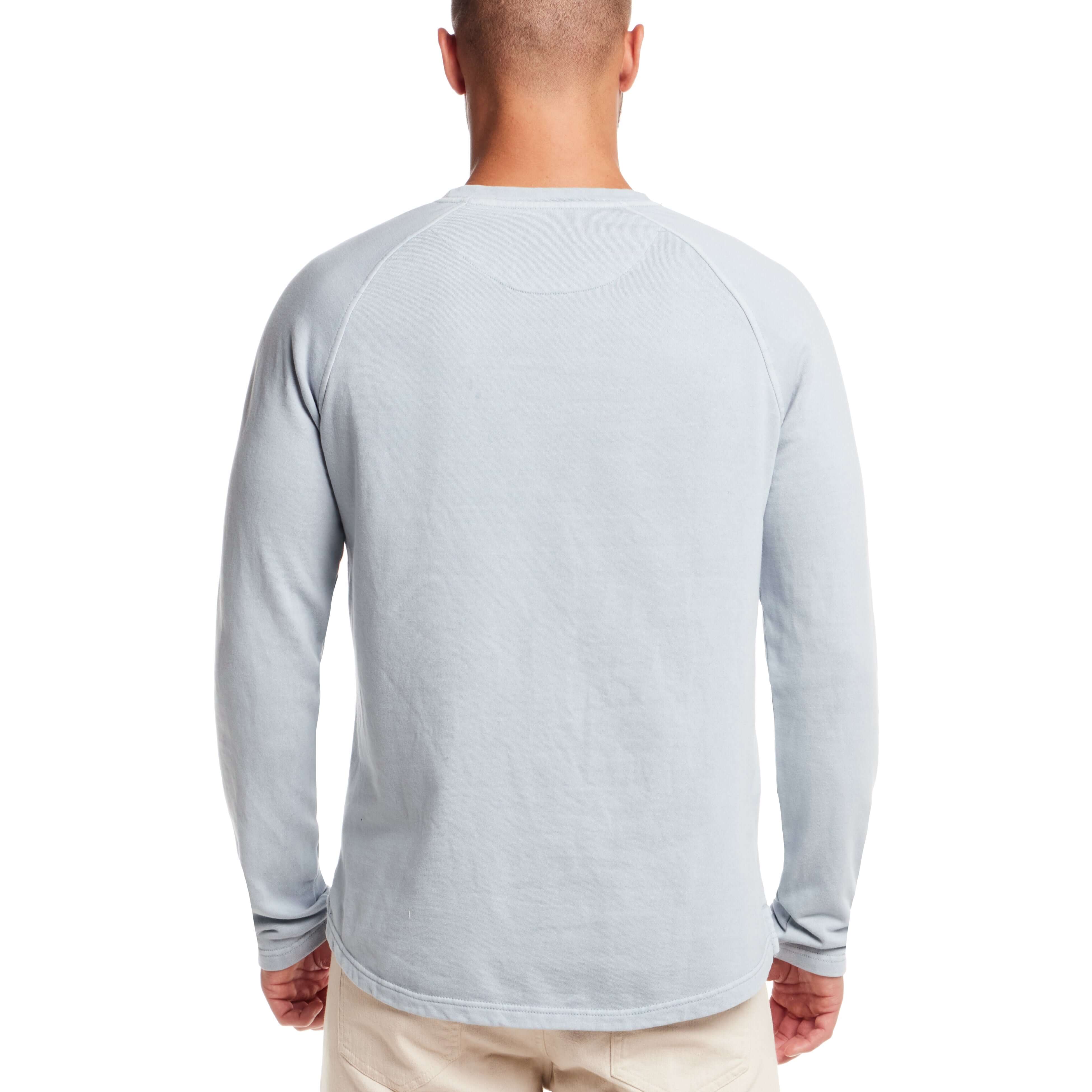 Man wearing a dusty blue long sleeve raglan sweatshirt, showcasing the back design and classic fit.
