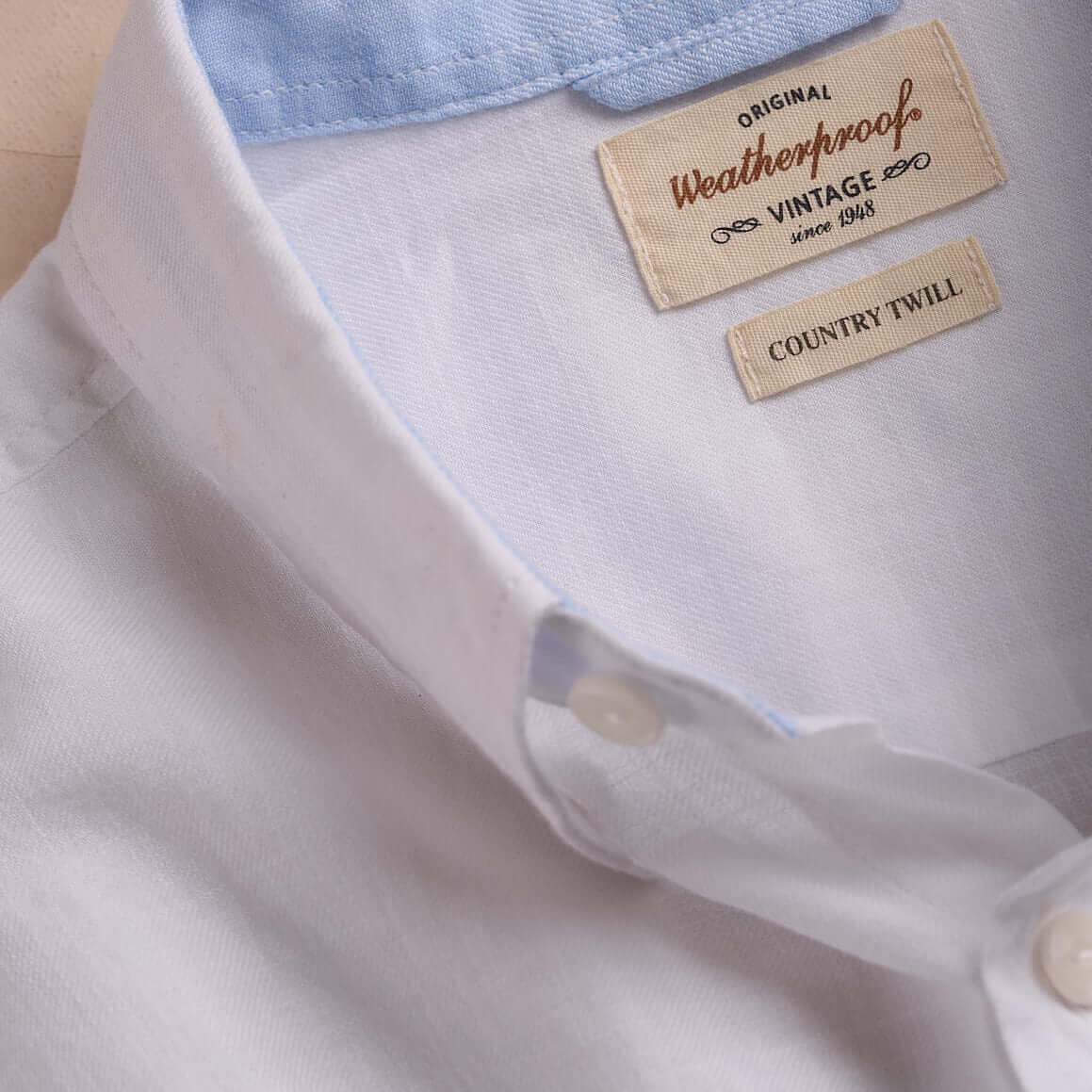 Close-up of a white cotton twill shirt showcasing the collar and labels, highlighting vintage Weatherproof quality.