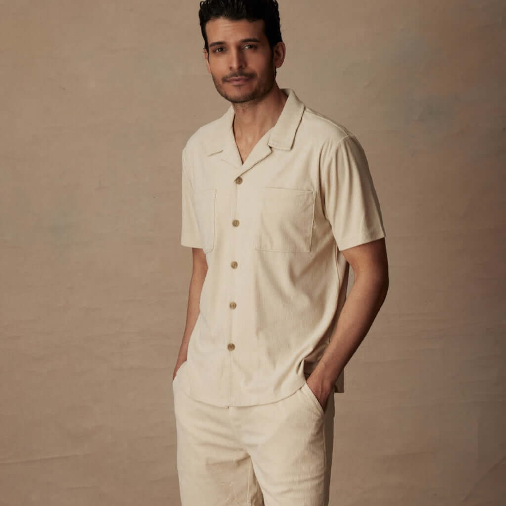 Man wearing a short sleeve corduroy cabana shirt in cream with a classic fit, featuring double chest pockets.