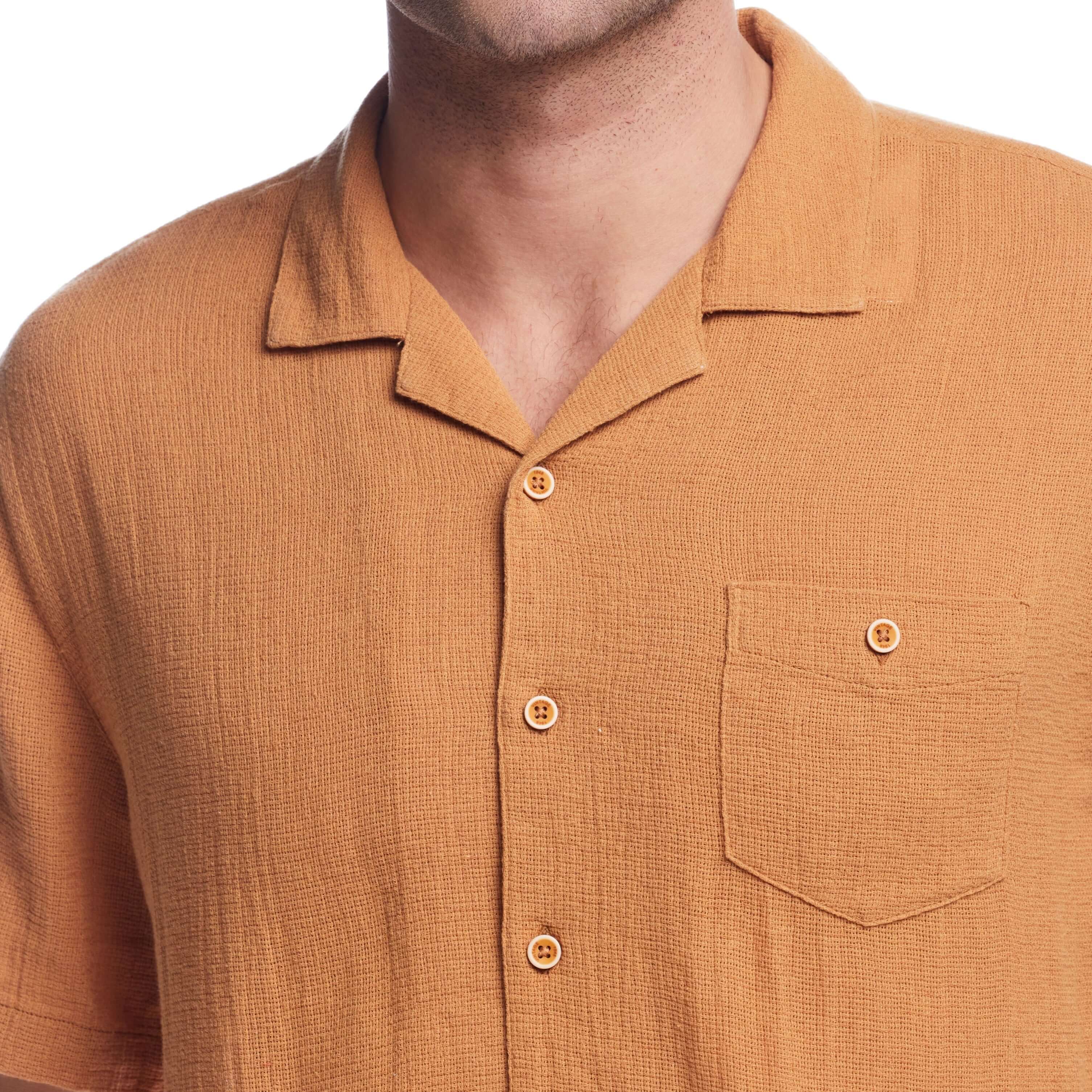 Close-up of a man wearing a Biscuit short sleeve cotton linen Airtex shirt with a camp collar and button-down pocket.