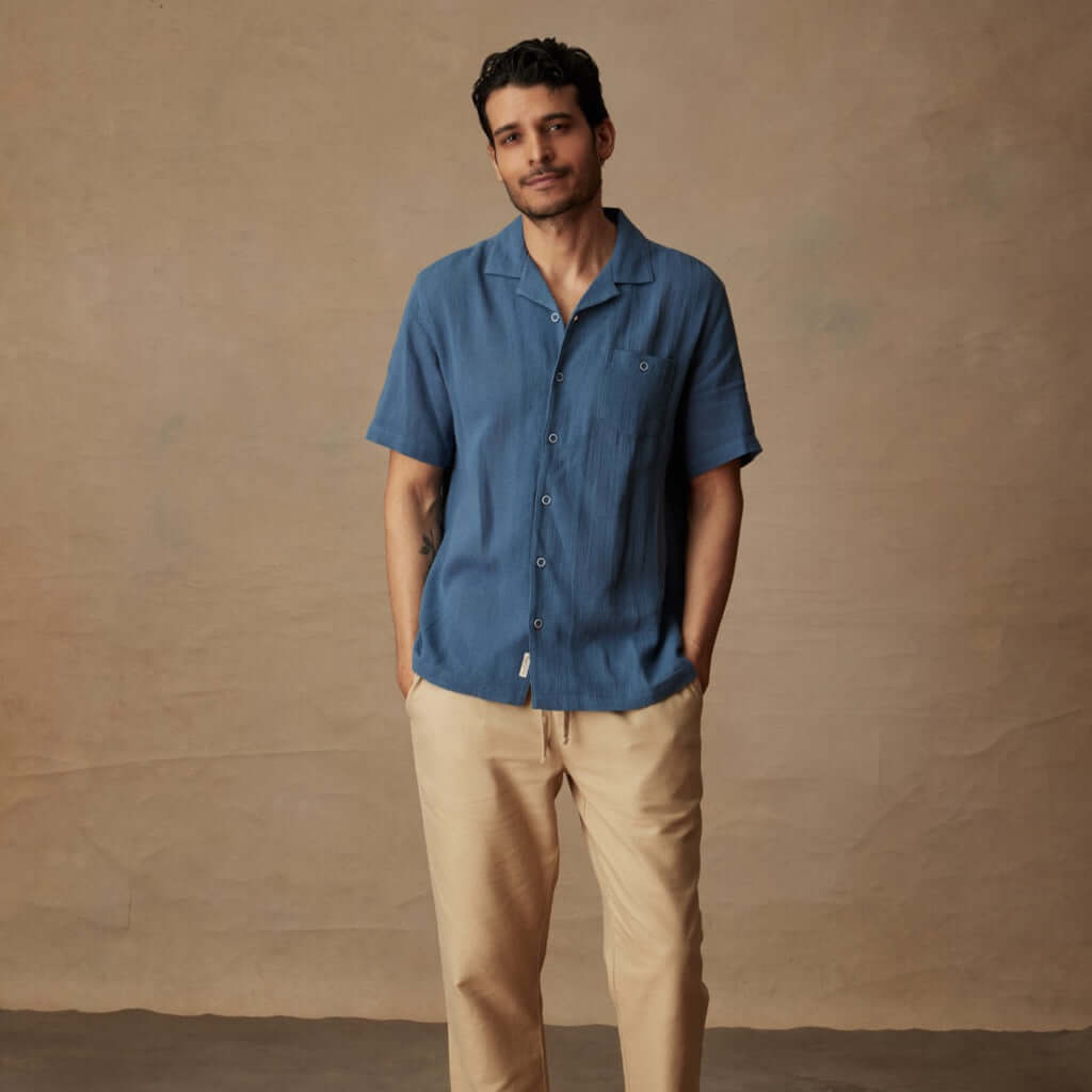 Model wearing a Short Sleeve Cotton Linen Airtex Shirt in Blue Ashes, styled for a casual vacation look.