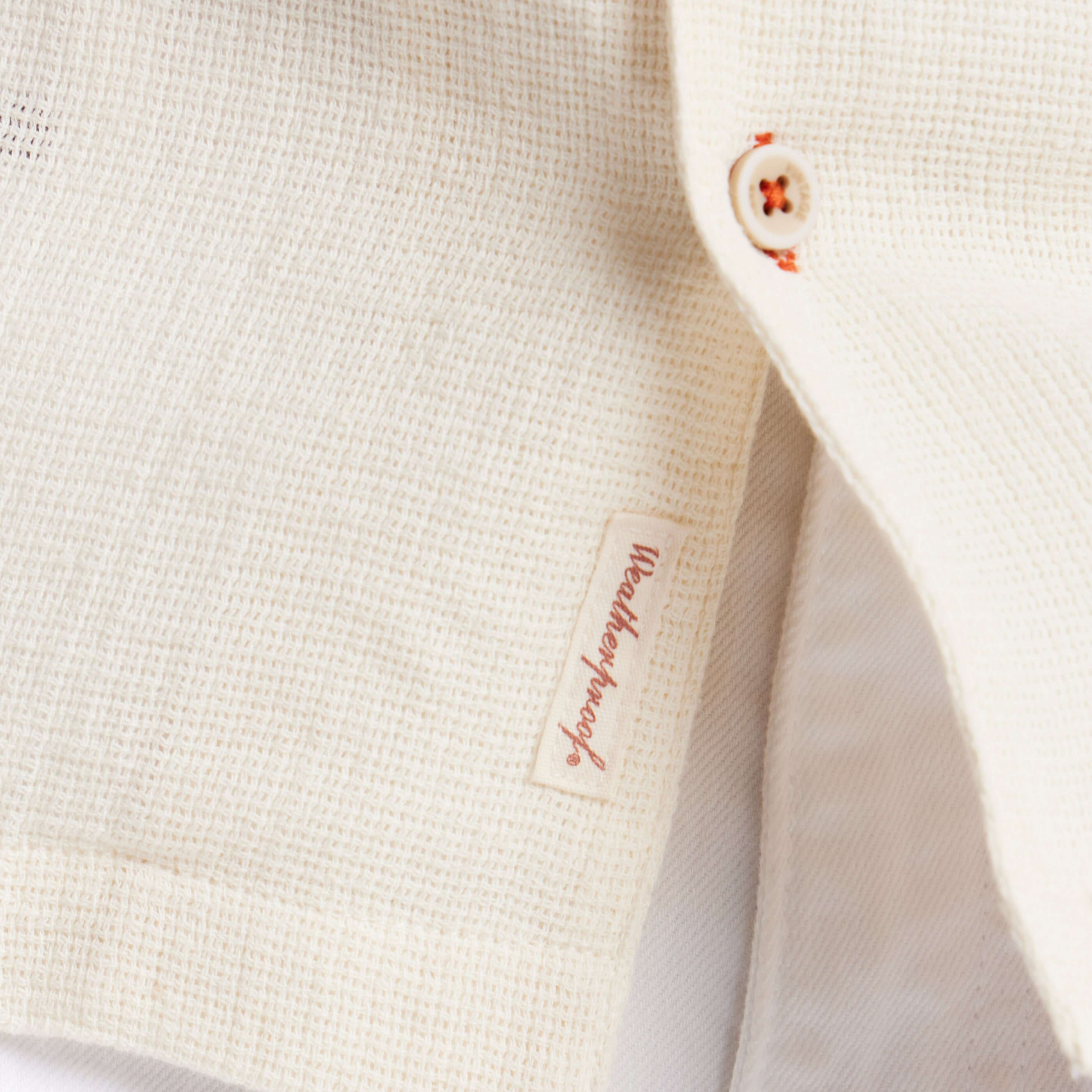 Close-up of cream short sleeve Airtex shirt showcasing the camp collar and button details.