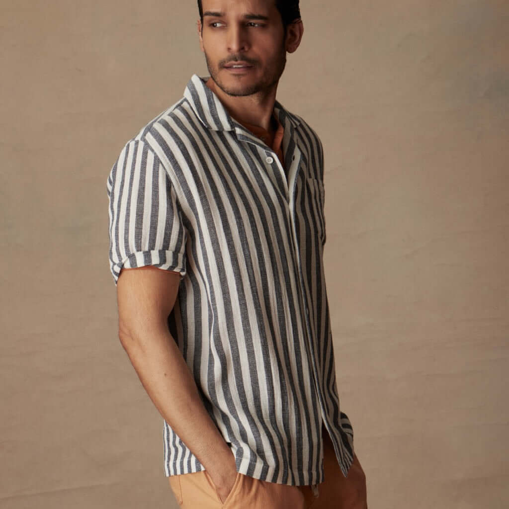 Man wearing a short sleeve cotton linen Airtex stripe shirt in insignia blue, perfect for vacation style.