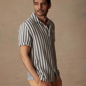 Man wearing a short sleeve cotton linen Airtex stripe shirt in insignia blue, perfect for vacation style.