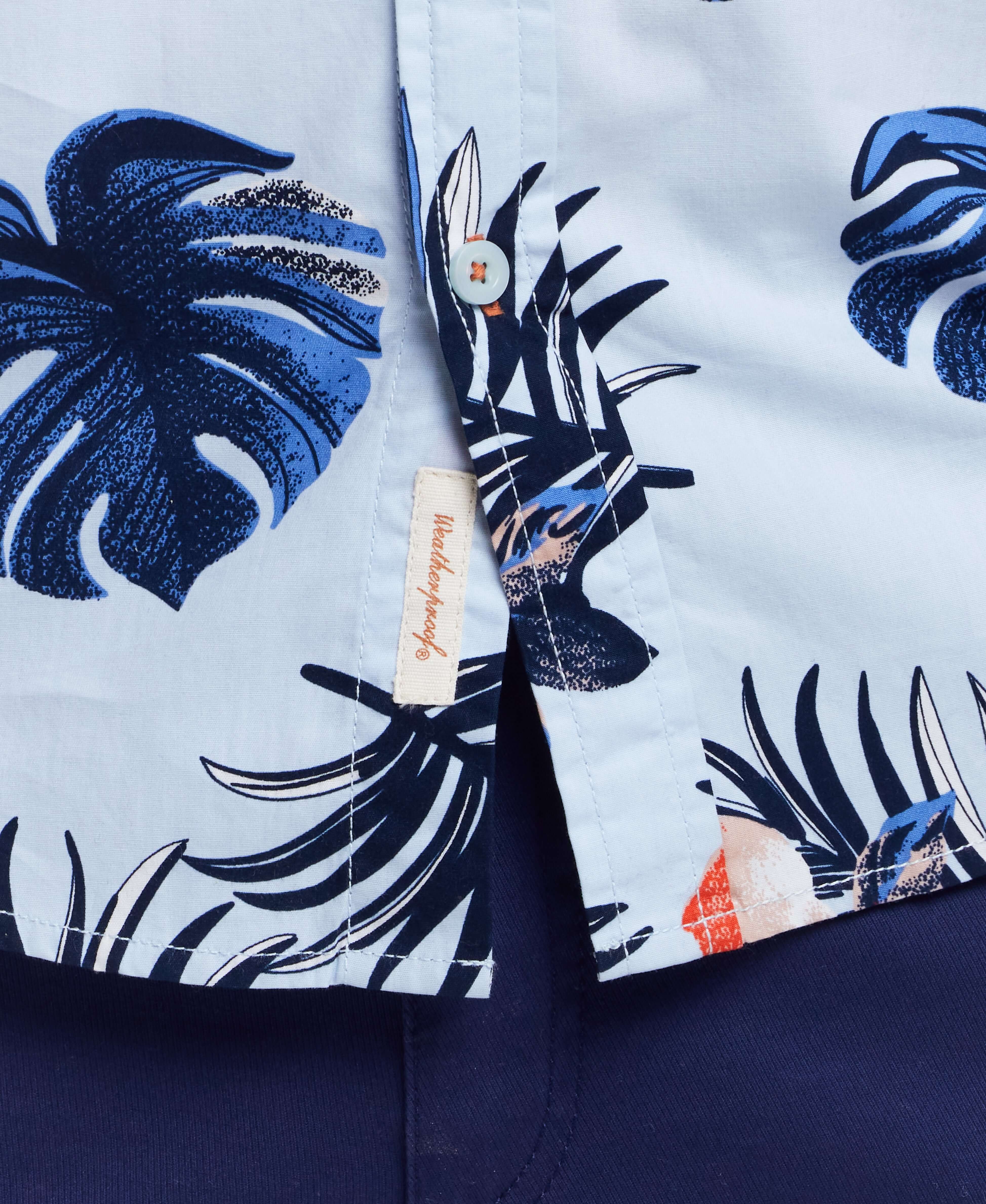 Short sleeve cotton poplin shirt featuring tropical leaves pattern in blue and white, showcasing button-down details.