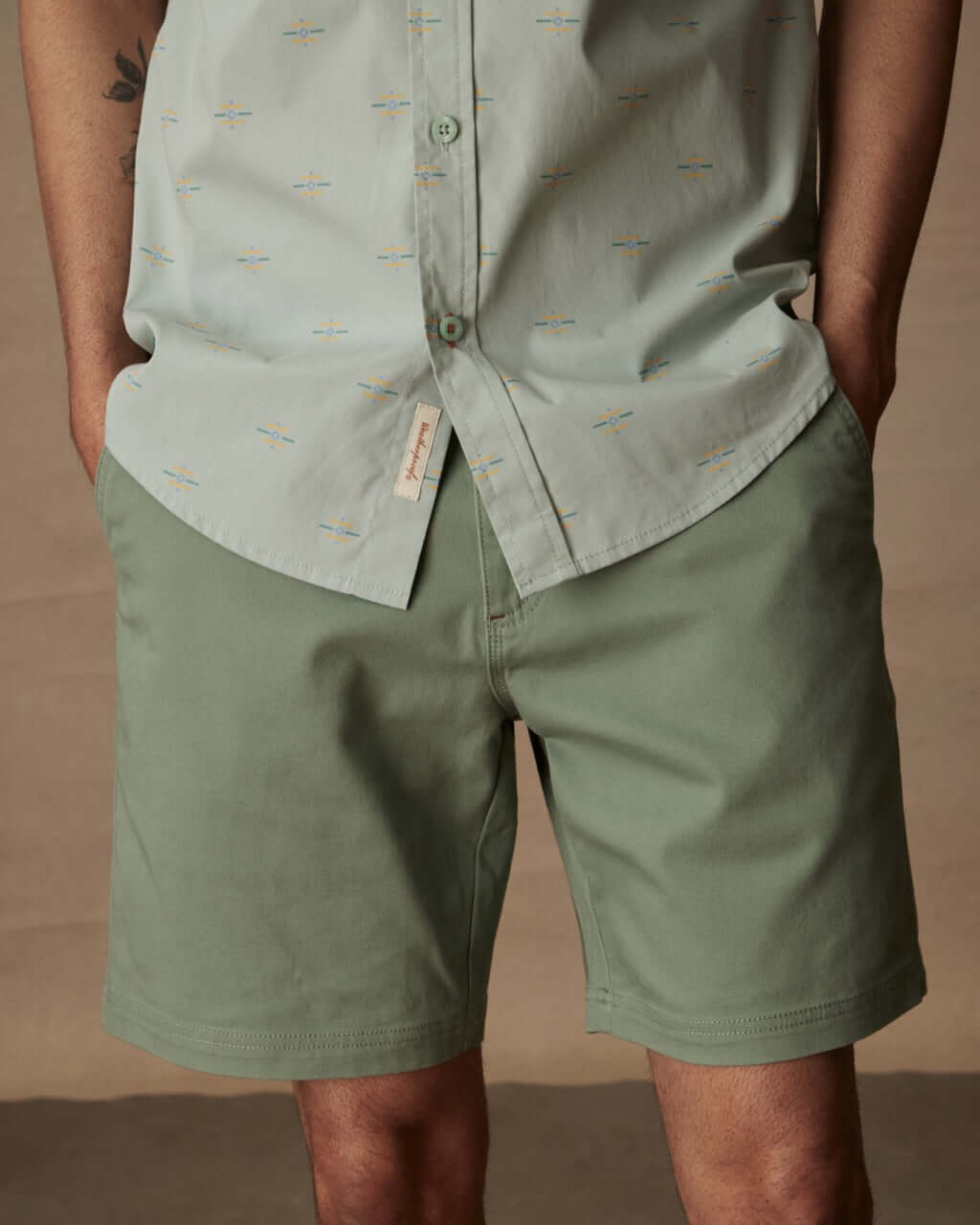 Man wearing a short sleeve cotton poplin shirt in teal mist and green shorts, showcasing a casual summer outfit.