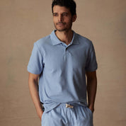 Model wearing a short sleeve, fjord blue honeycomb pique polo shirt with a comfortable fit and casual style.
