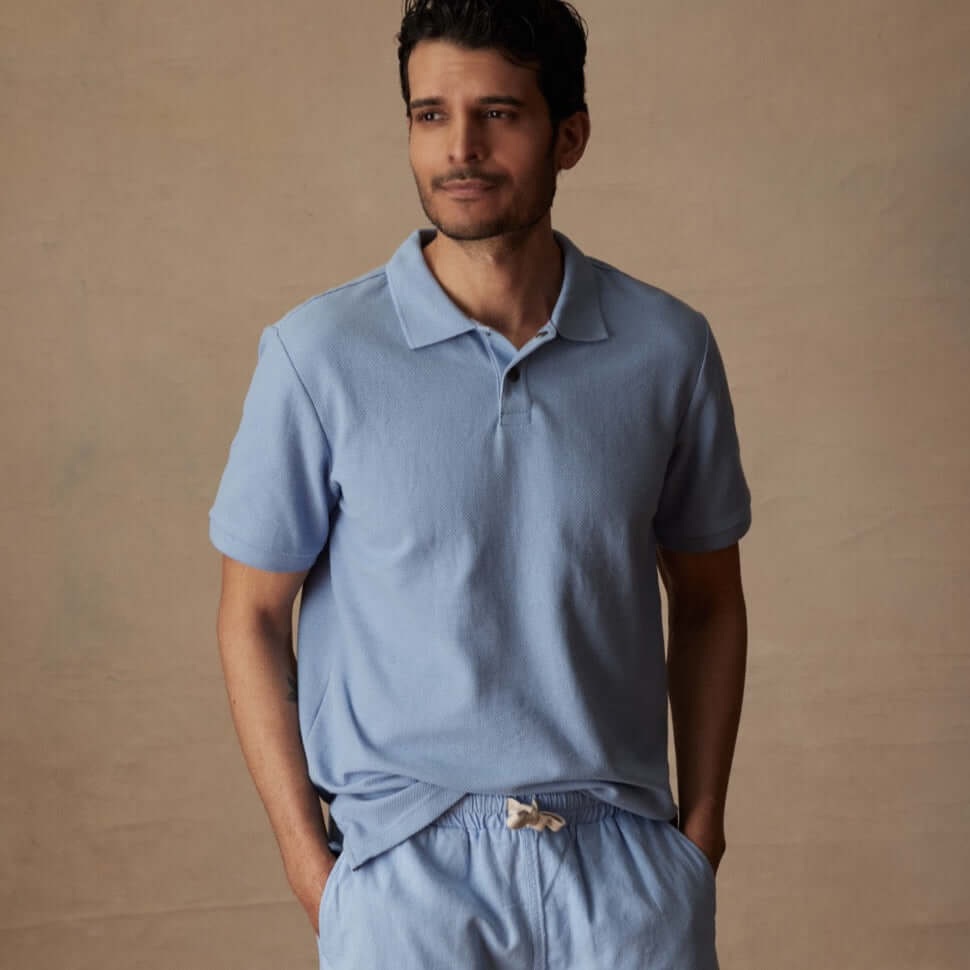 Model wearing a short sleeve, fjord blue honeycomb pique polo shirt with a comfortable fit and casual style.