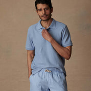 Model wearing Short Sleeve Honeycomb Pique Polo Shirt in Fjord Blue, styled with casual shorts in a neutral setting.