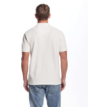 Back view of a man wearing a short sleeve ivory honeycomb pique polo shirt, showcasing a classic fit and ribbed collar.