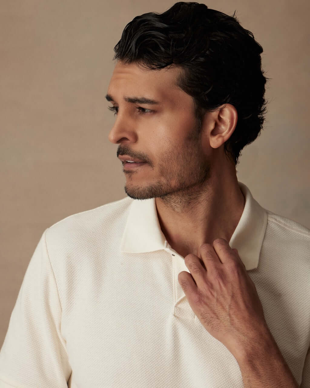 Model wearing an ivory short sleeve honeycomb pique polo shirt with a classic fit and ribbed collar.