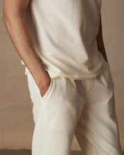 Close-up of a model's torso wearing an ivory short sleeve honeycomb pique polo shirt, paired with light-colored trousers.