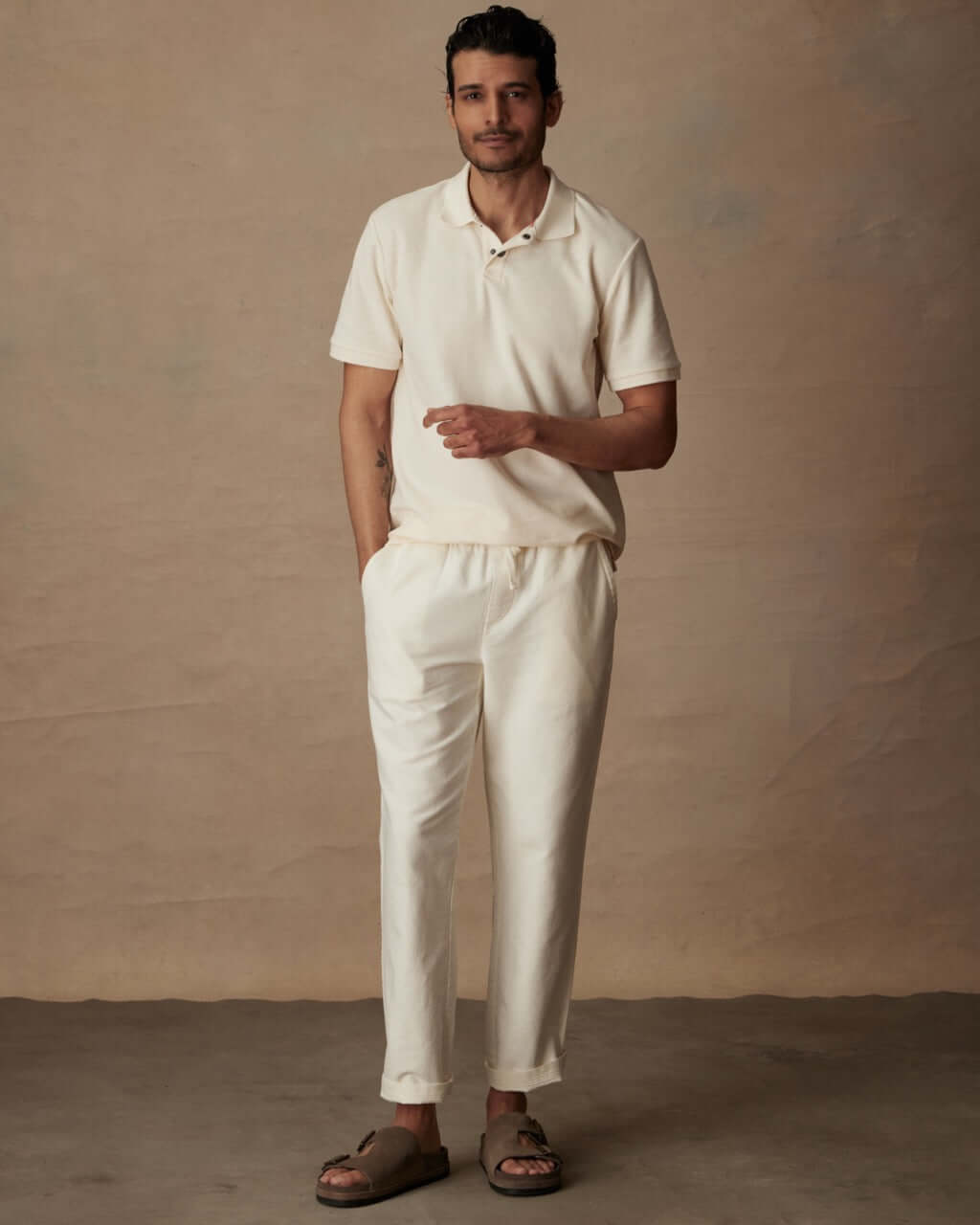 Short sleeve ivory honeycomb pique polo shirt on model, paired with casual pants and sandals, showcasing classic fit and style.