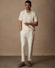 Short sleeve ivory honeycomb pique polo shirt on model, paired with casual pants and sandals, showcasing classic fit and style.