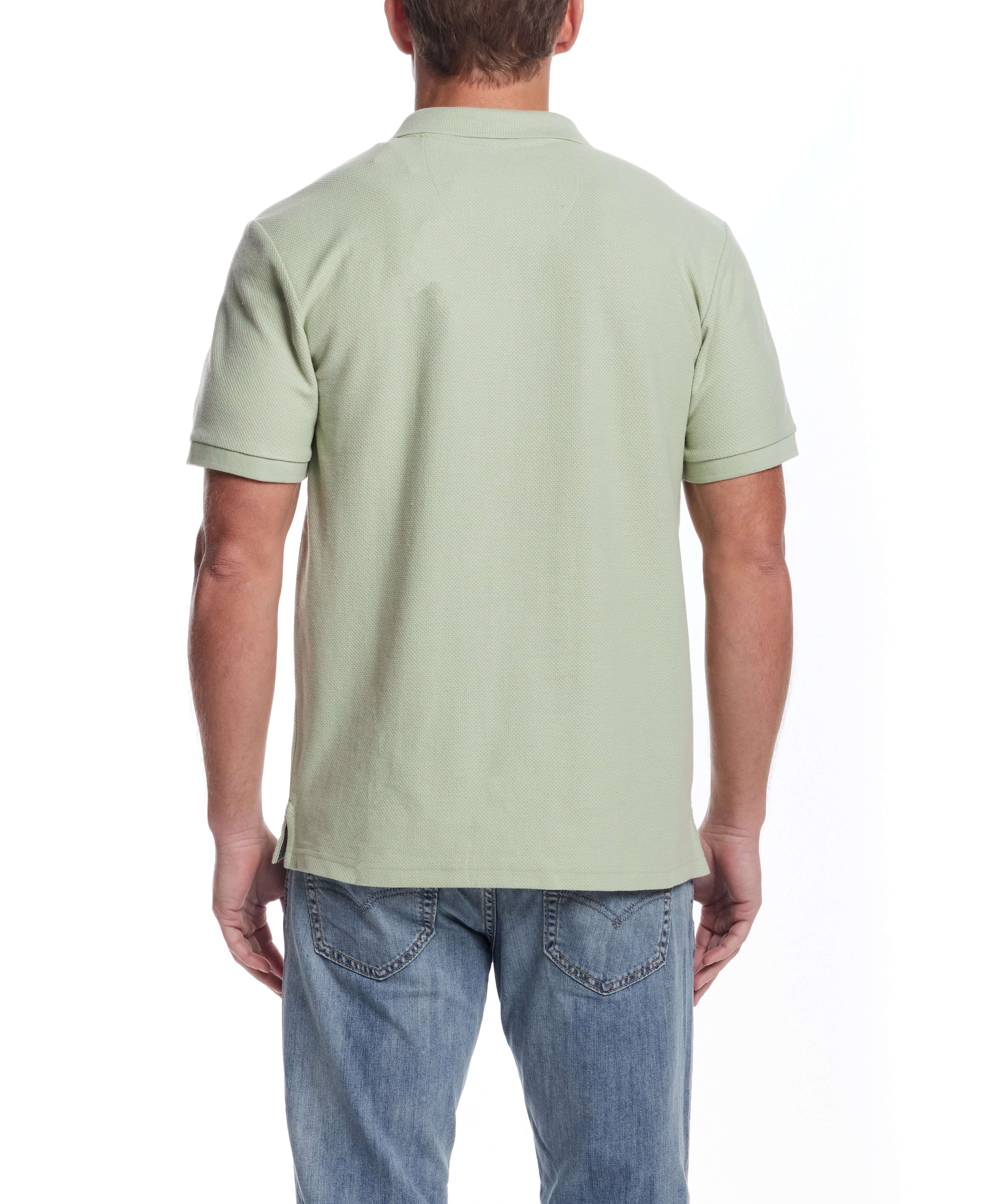 Back view of a light green short sleeve honeycomb pique polo shirt on a model, showcasing classic fit and ribbed cuffs.