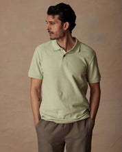 Man modeling a light green short sleeve honeycomb pique polo shirt, featuring a classic fit and ribbed collar.